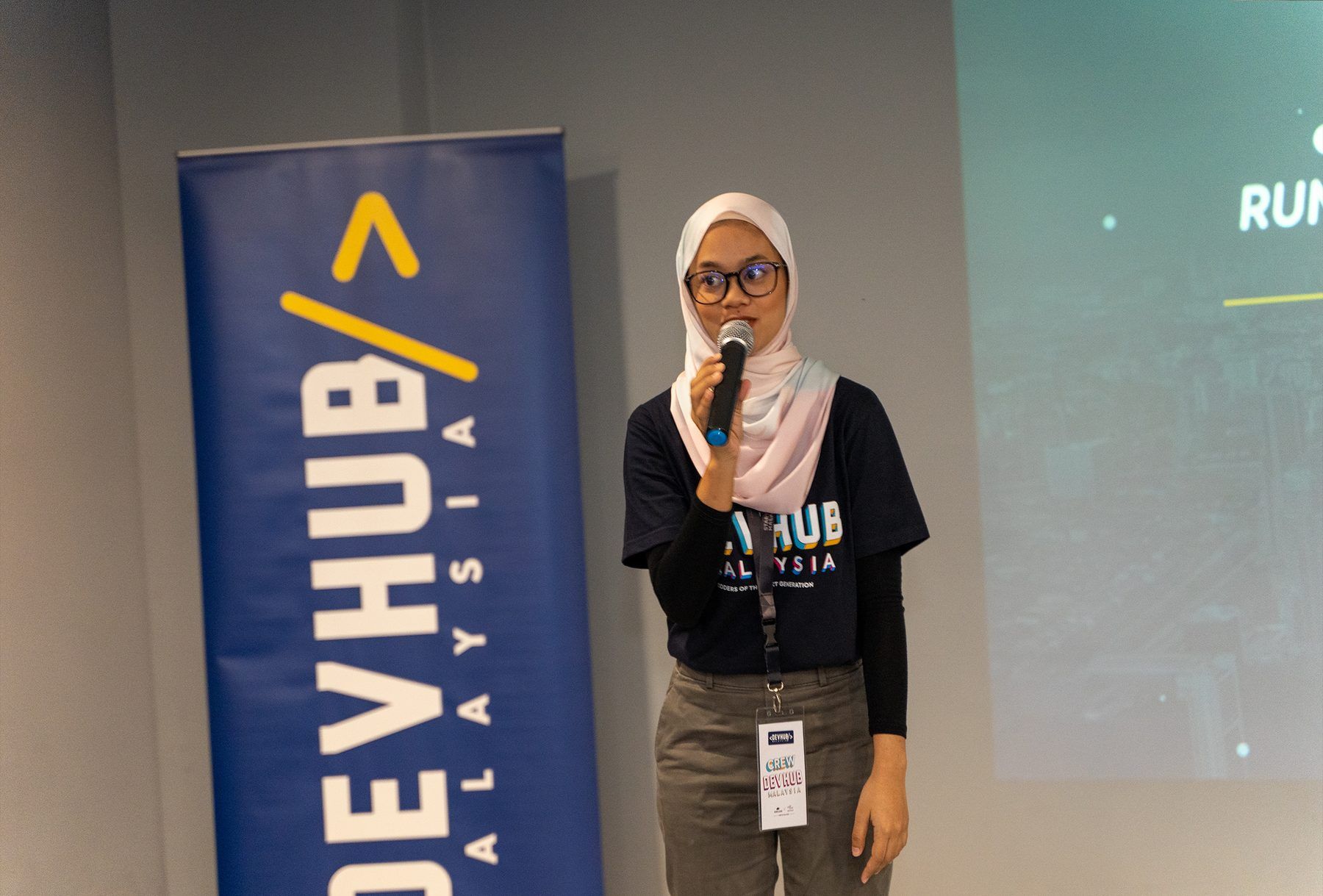 A speaker delivering a talk beside the DevHub Malaysia banner